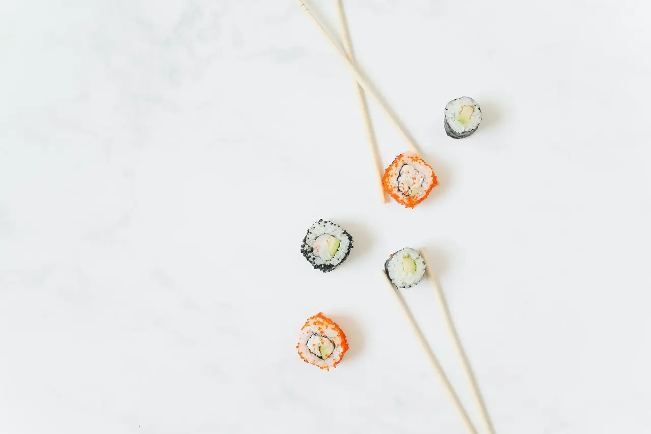 sushi 5Different types of mini sushi rolls placed on a white background, paired with chopsticks